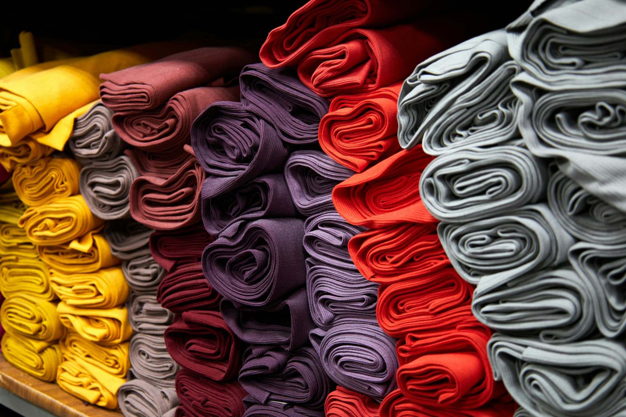 Folded fabric lengths in reds, greys and ochres
