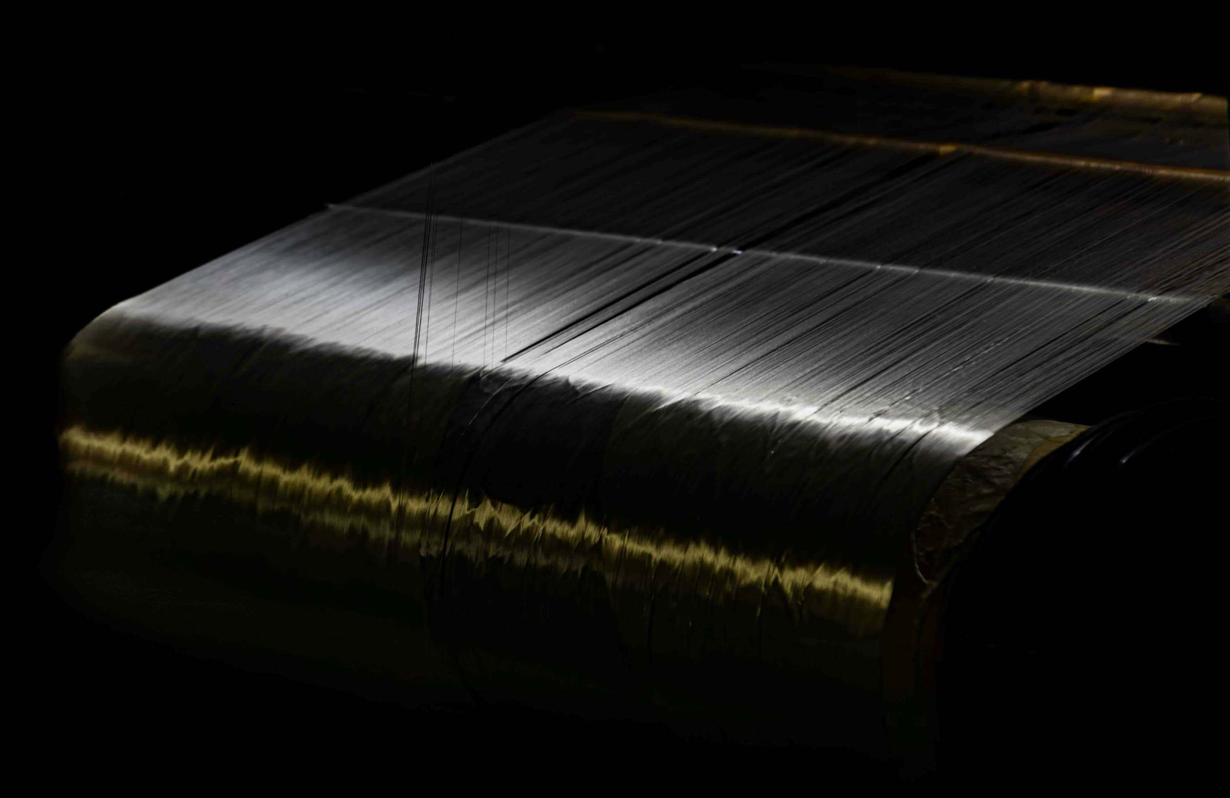 A warp beam of fine threads caught in low light