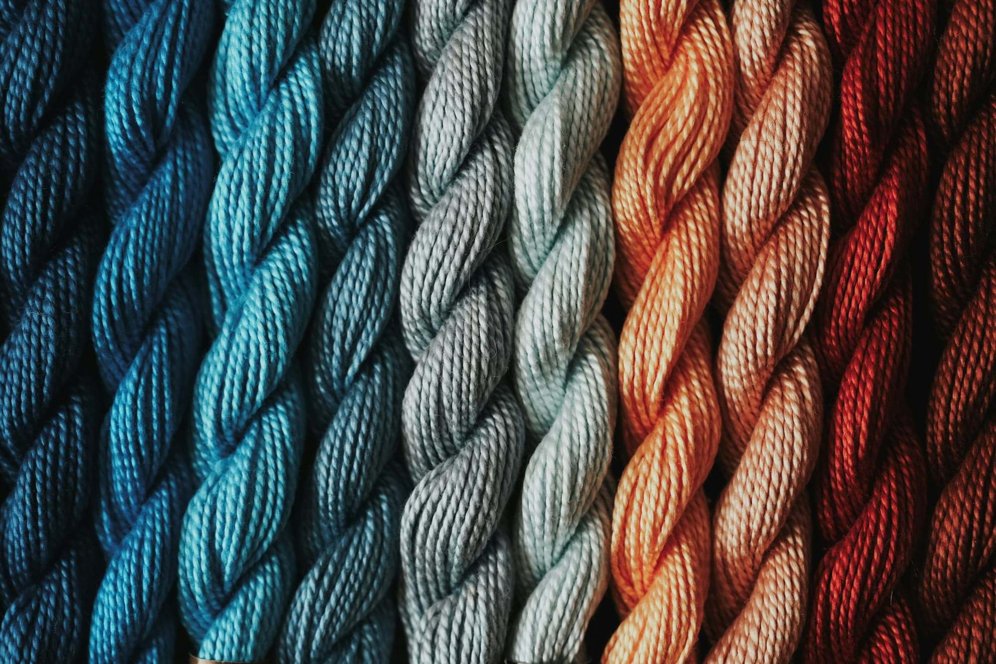 Hanks of dyed yarn in teal, grey, rust and red